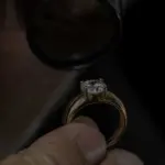 Ein Experte begutachtet einen goldenen Ring mit eingefasstem Stein aus nächster Nähe durch eine Lupe.